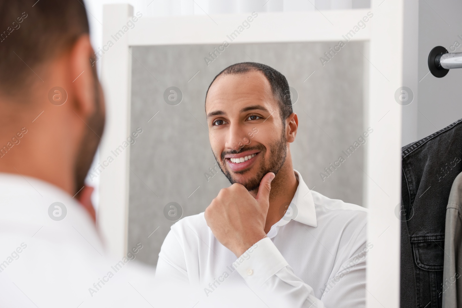 Photo of Smiling man looking at mirror at home