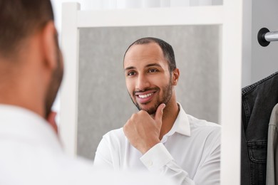 Smiling man looking at mirror at home