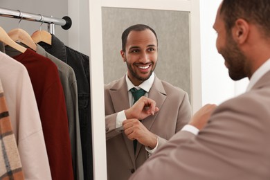 Photo of Smiling man dressing near mirror at home