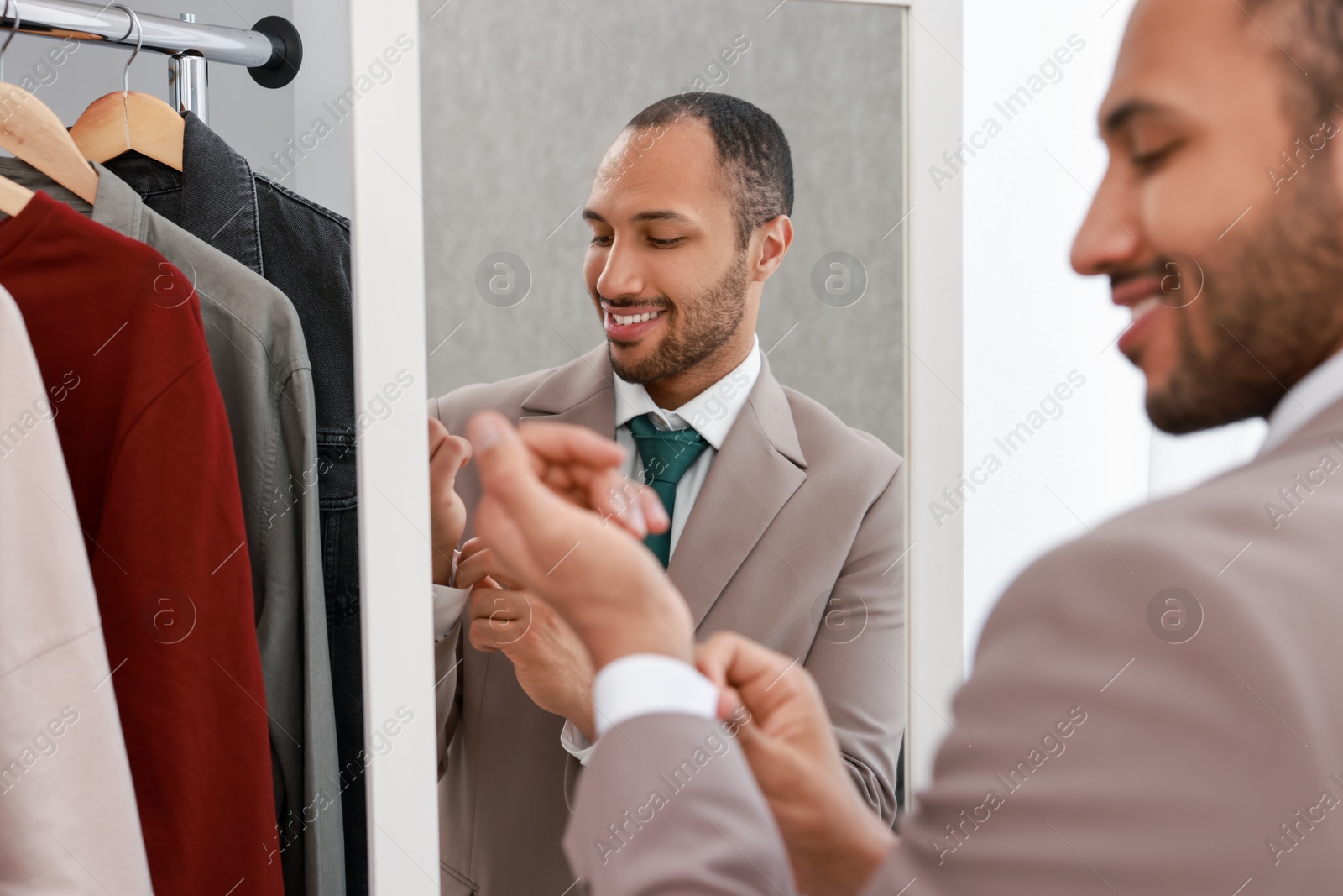 Photo of Smiling man dressing near mirror at home