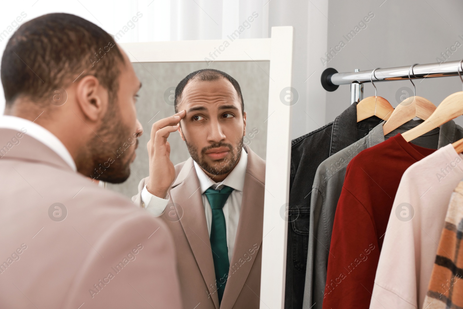 Photo of Worried man looking at mirror at home