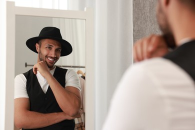 Smiling man looking at mirror at home