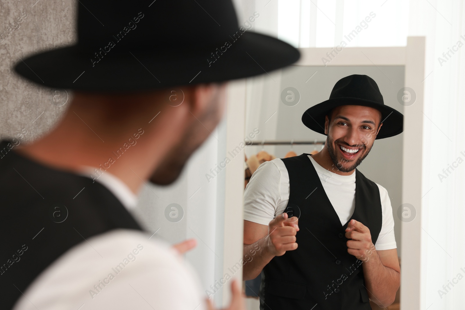 Photo of Smiling man looking at mirror at home