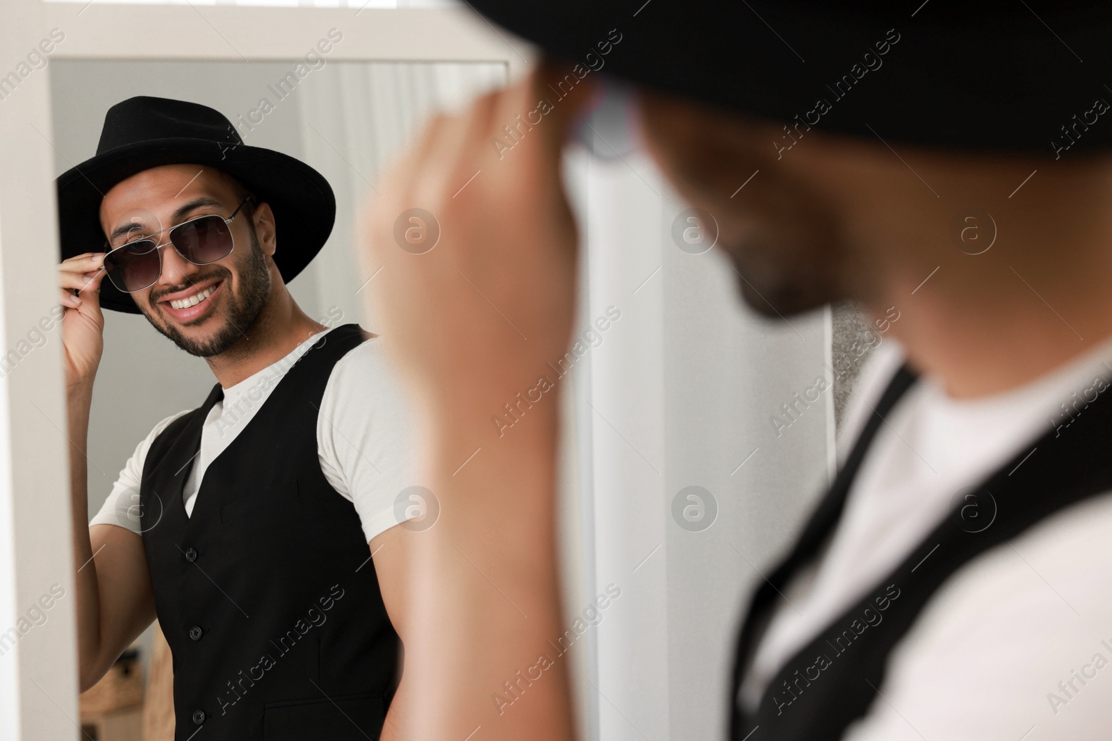 Photo of Smiling man looking at mirror at home