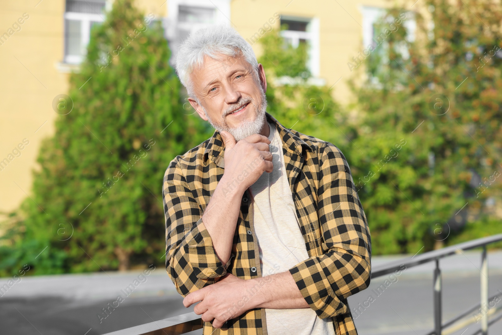 Photo of Portrait of smiling senior man in checkered shirt outdoors