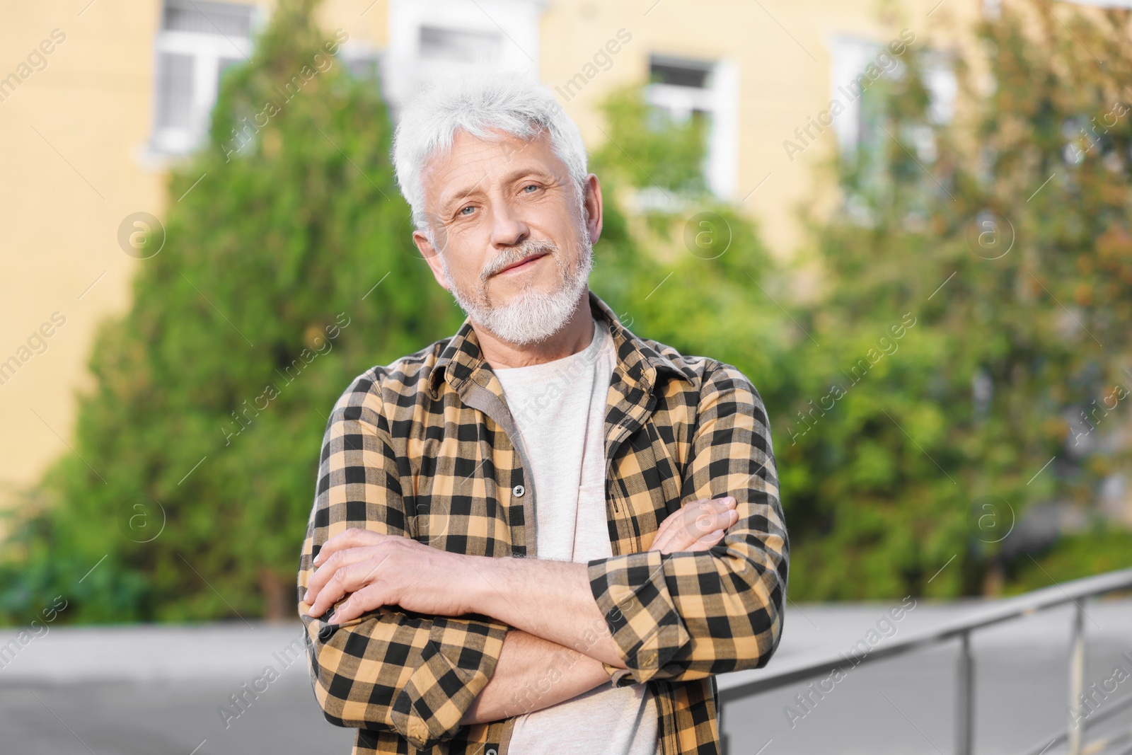 Photo of Portrait of senior man with crossed arms outdoors