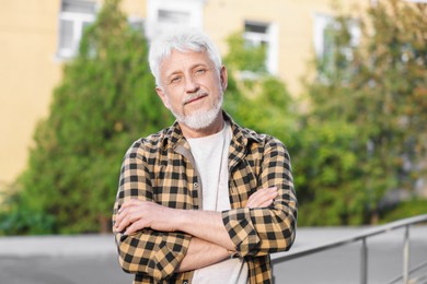 Photo of Portrait of senior man with crossed arms outdoors