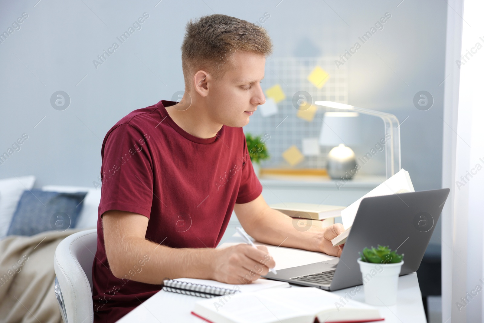 Photo of Student preparing for exam with laptop at table indoors