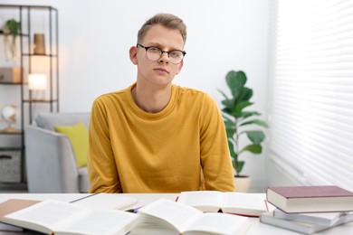 Photo of Preparing for exam. Student with books at table indoors