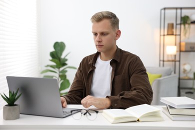 Photo of Student preparing for exam with laptop at table indoors