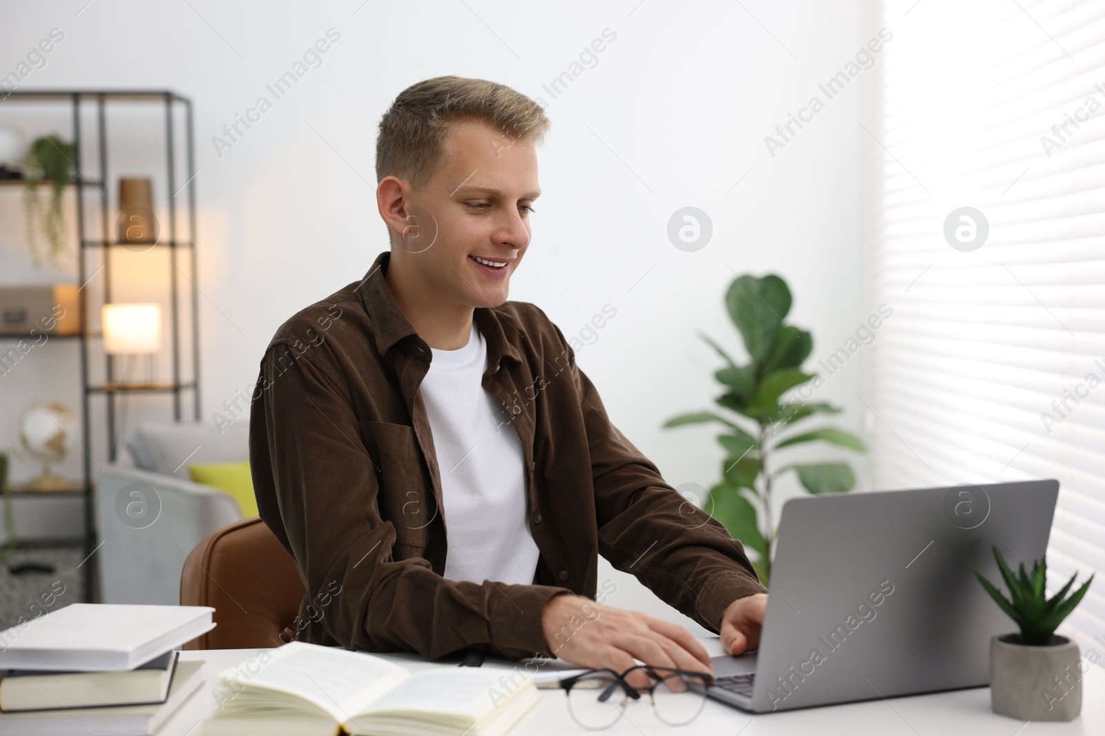 Photo of Student preparing for exam with laptop at table indoors