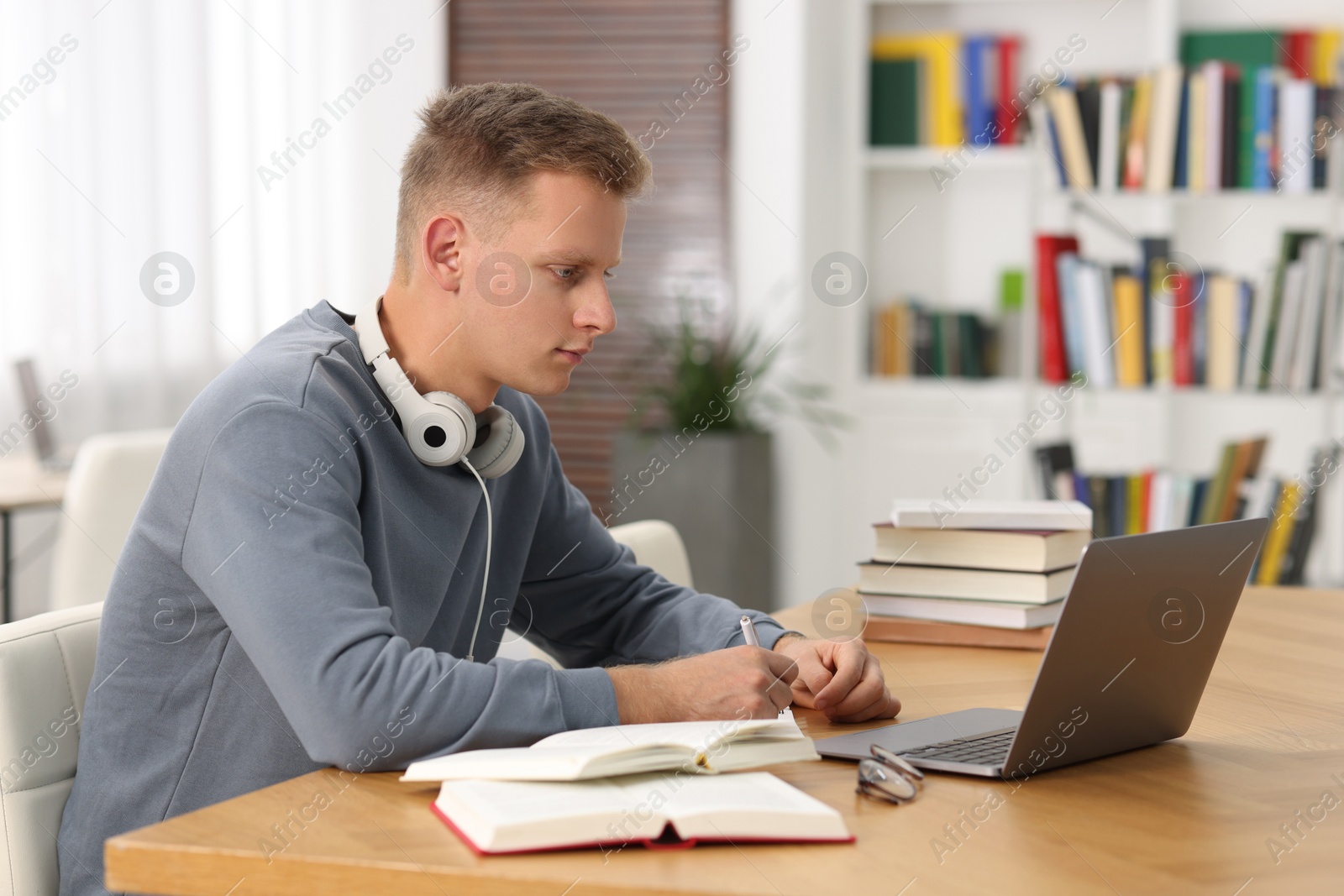 Photo of Student preparing for exam with laptop at table indoors