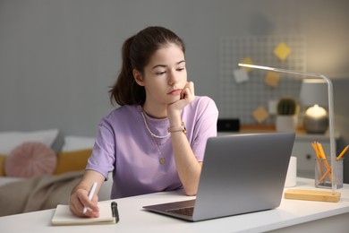 Photo of Student preparing for exam with laptop at table indoors