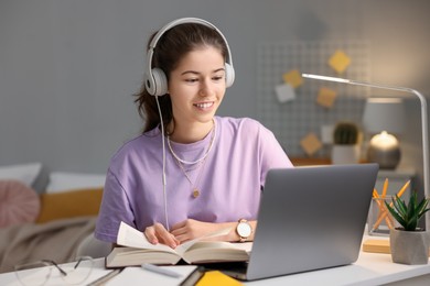 Photo of Student preparing for exam with laptop at table indoors