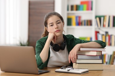 Photo of Preparing for exam. Student with laptop and books at table indoors