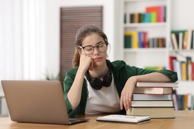 Photo of Preparing for exam. Tired student with laptop and books at table indoors