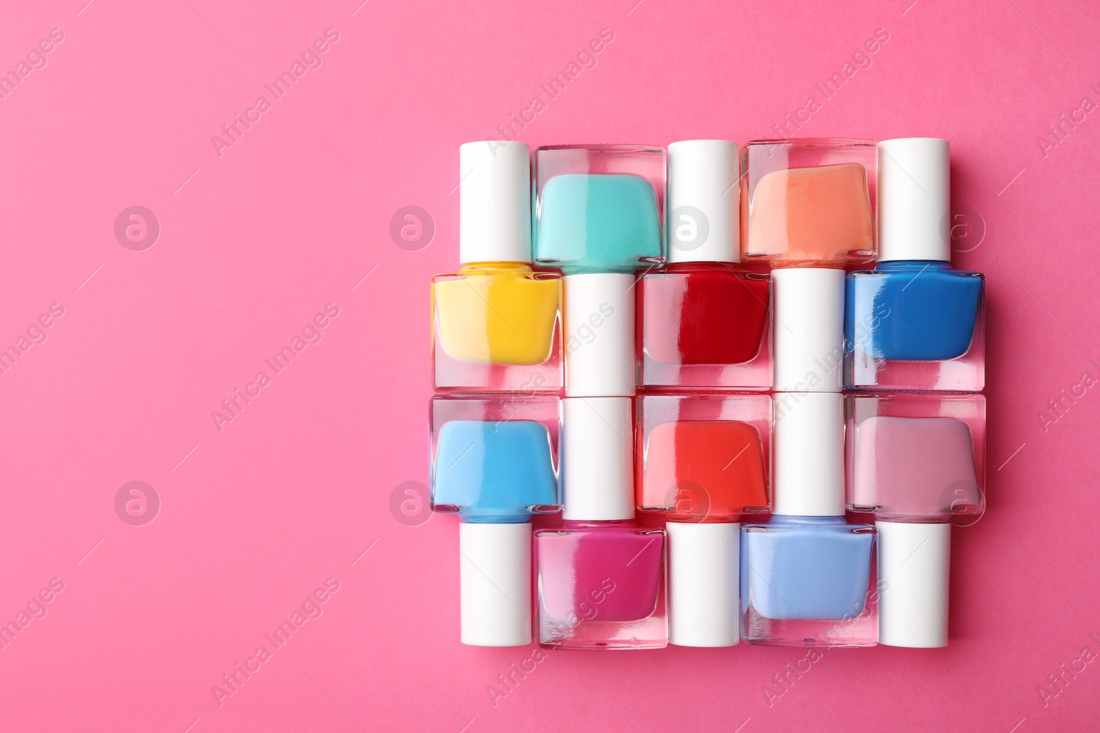 Photo of Set of different nail polishes on pink background, flat lay. Space for text