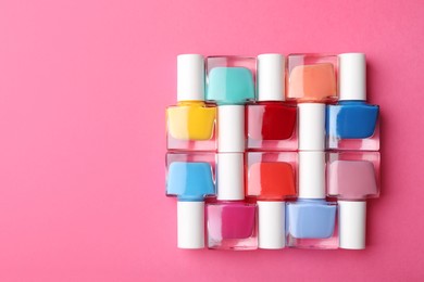 Photo of Set of different nail polishes on pink background, flat lay. Space for text