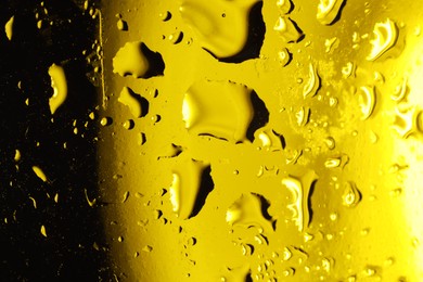 Photo of Water drops on dark yellow glass surface, macro view