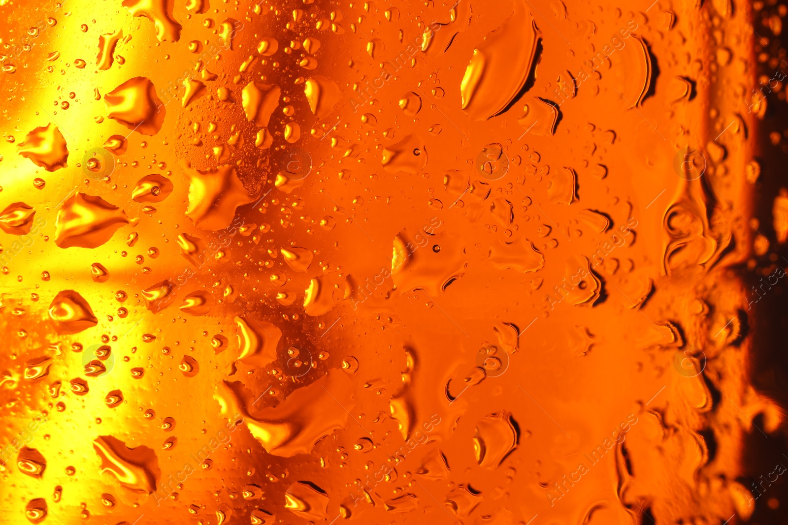 Photo of Water drops on orange glass surface, macro view