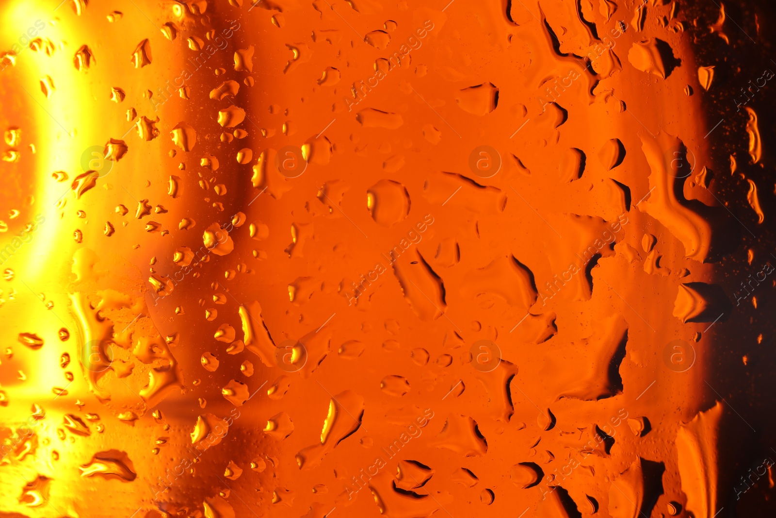 Photo of Water drops on orange glass surface, macro view