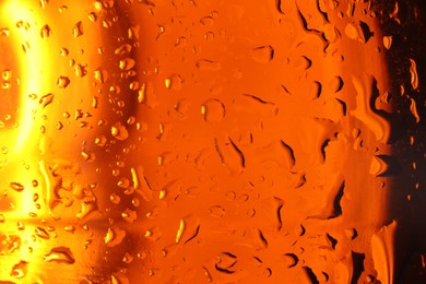 Photo of Water drops on orange glass surface, macro view