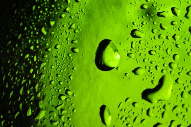 Photo of Water drops on green glass surface, macro view