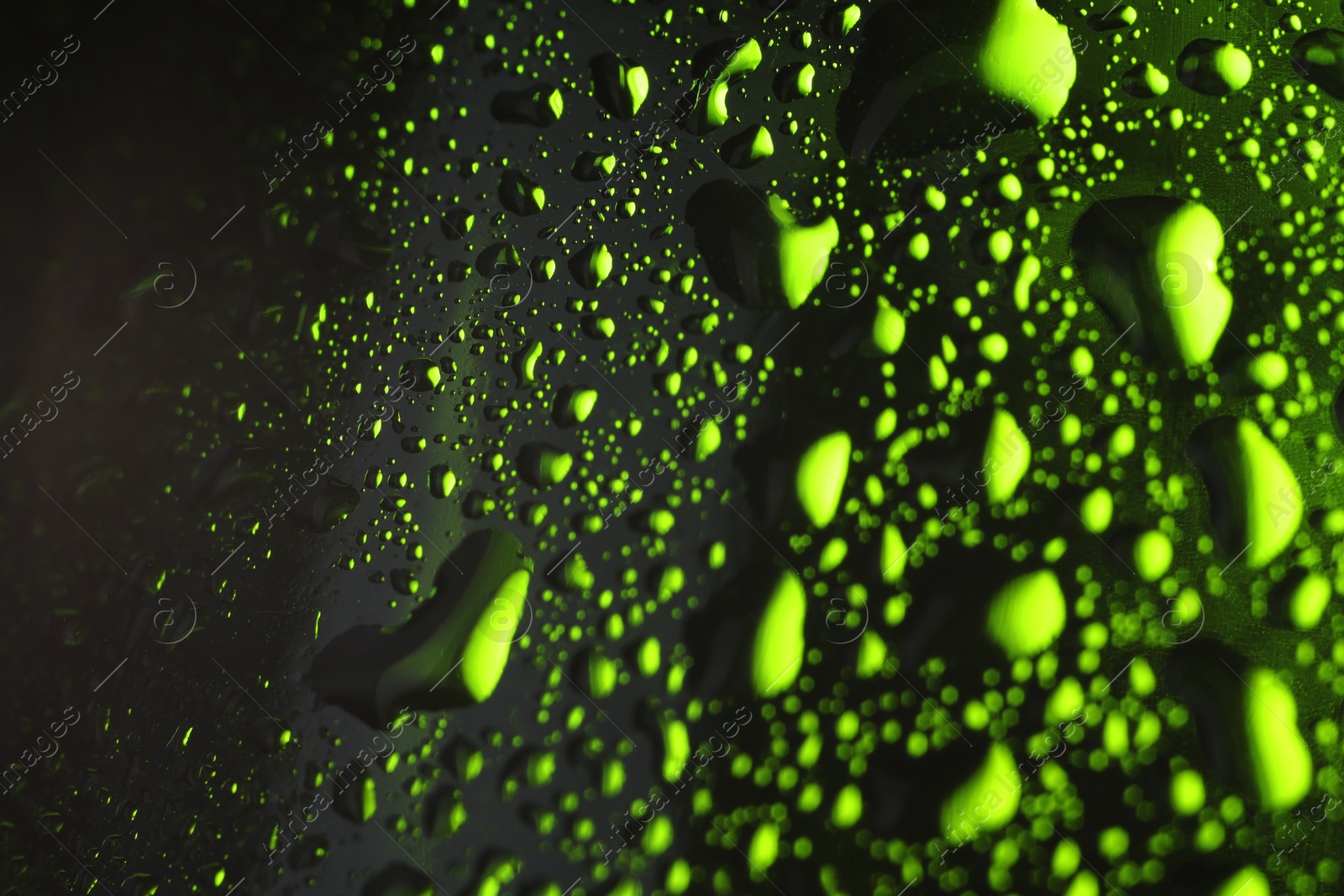 Photo of Water drops on dark green glass surface, macro view