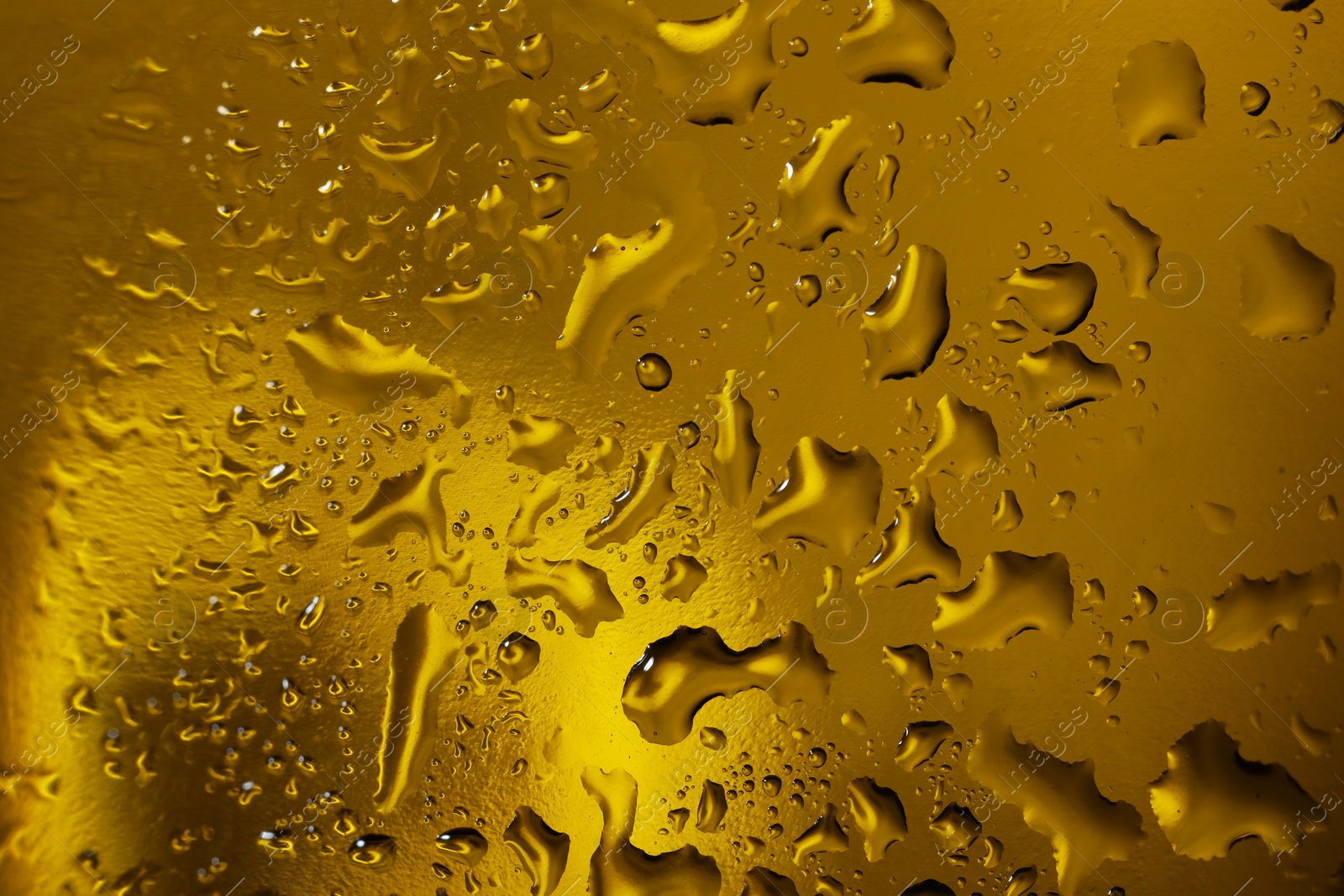 Photo of Water drops on dark yellow glass surface, macro view