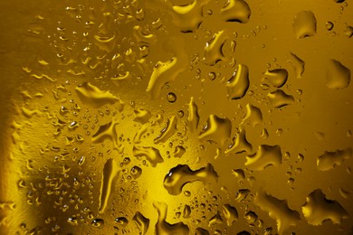 Water drops on dark yellow glass surface, macro view