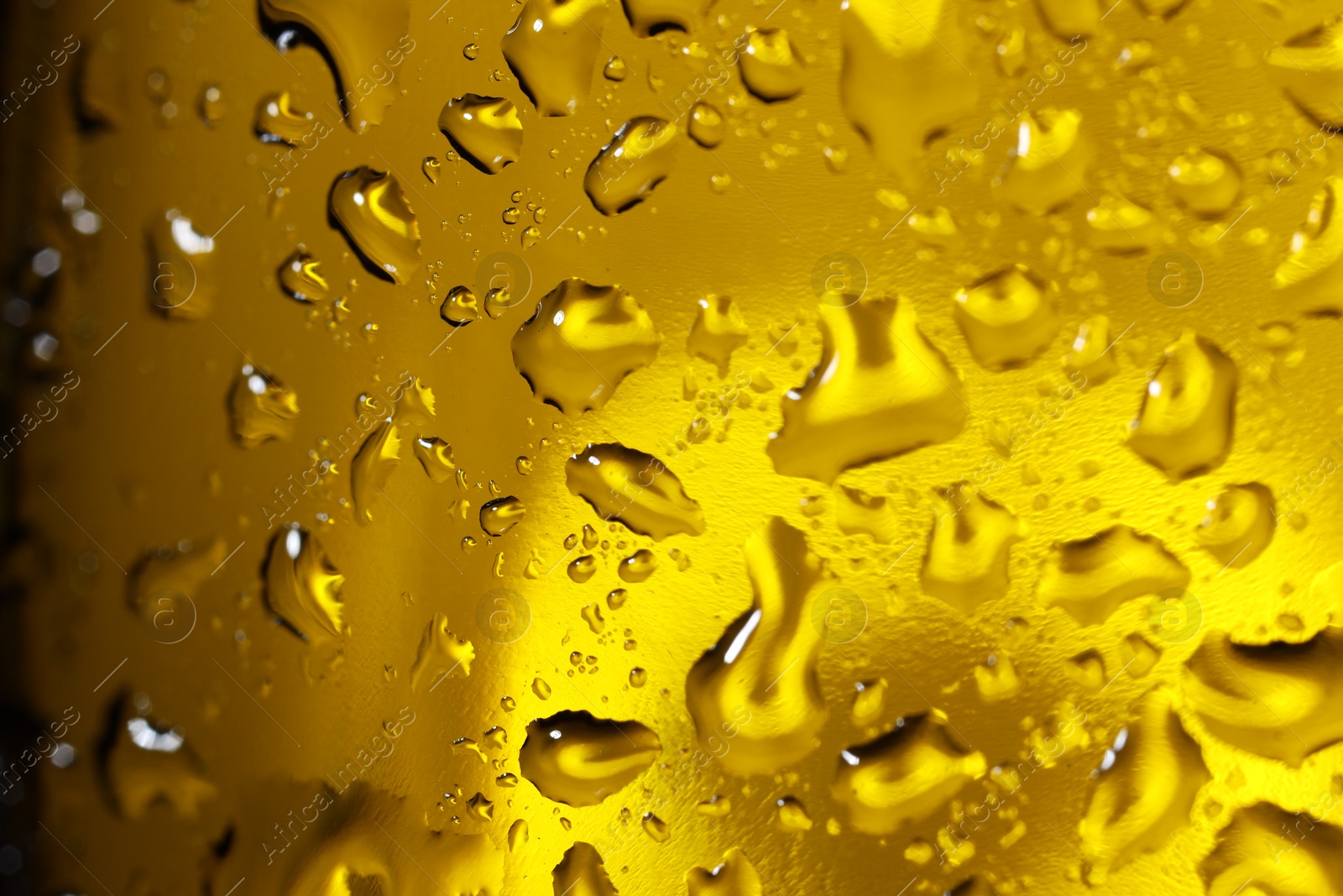 Photo of Water drops on dark yellow glass surface, macro view