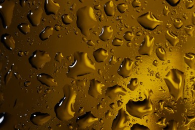 Water drops on dark yellow glass surface, macro view