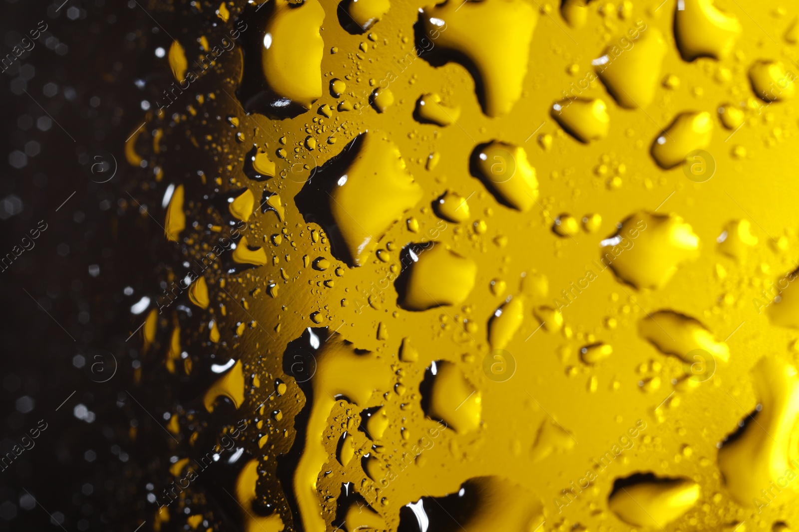 Photo of Water drops on dark yellow glass surface, macro view