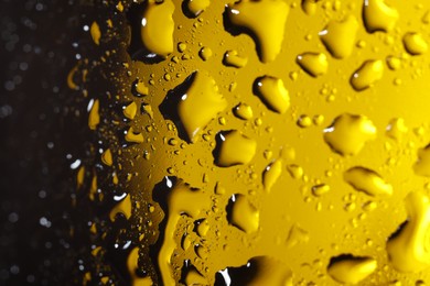 Water drops on dark yellow glass surface, macro view