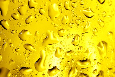 Water drops on yellow glass surface, macro view