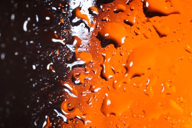 Photo of Water drops on orange glass surface, macro view