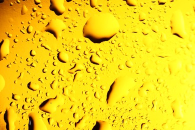 Water drops on yellow glass surface, macro view