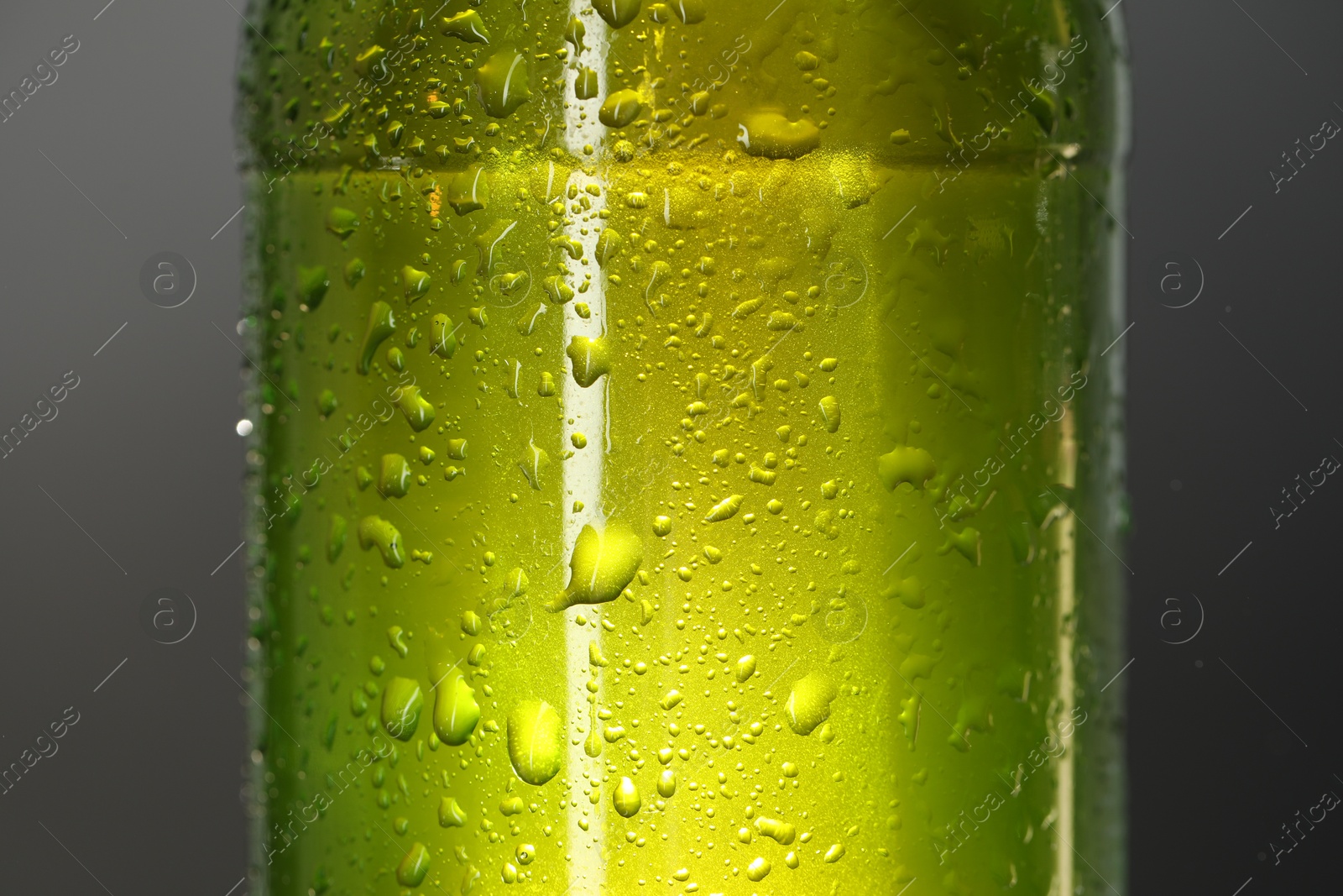 Photo of Glass bottle with condensation drops on grey background, closeup