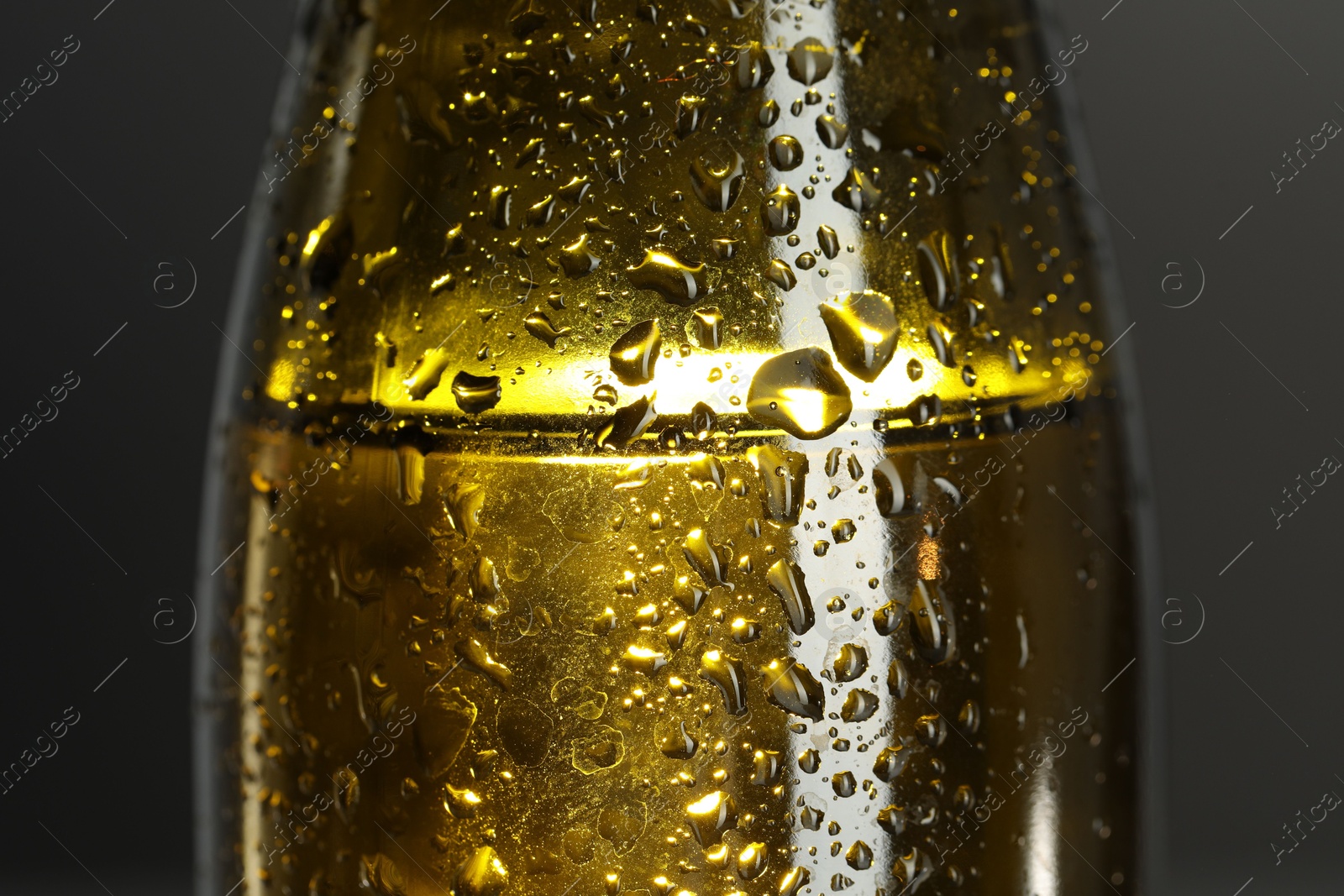 Photo of Glass bottle with condensation drops on grey background, macro view