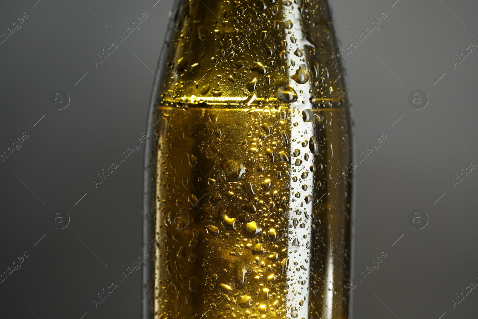 Photo of Glass bottle with condensation drops on grey background, closeup