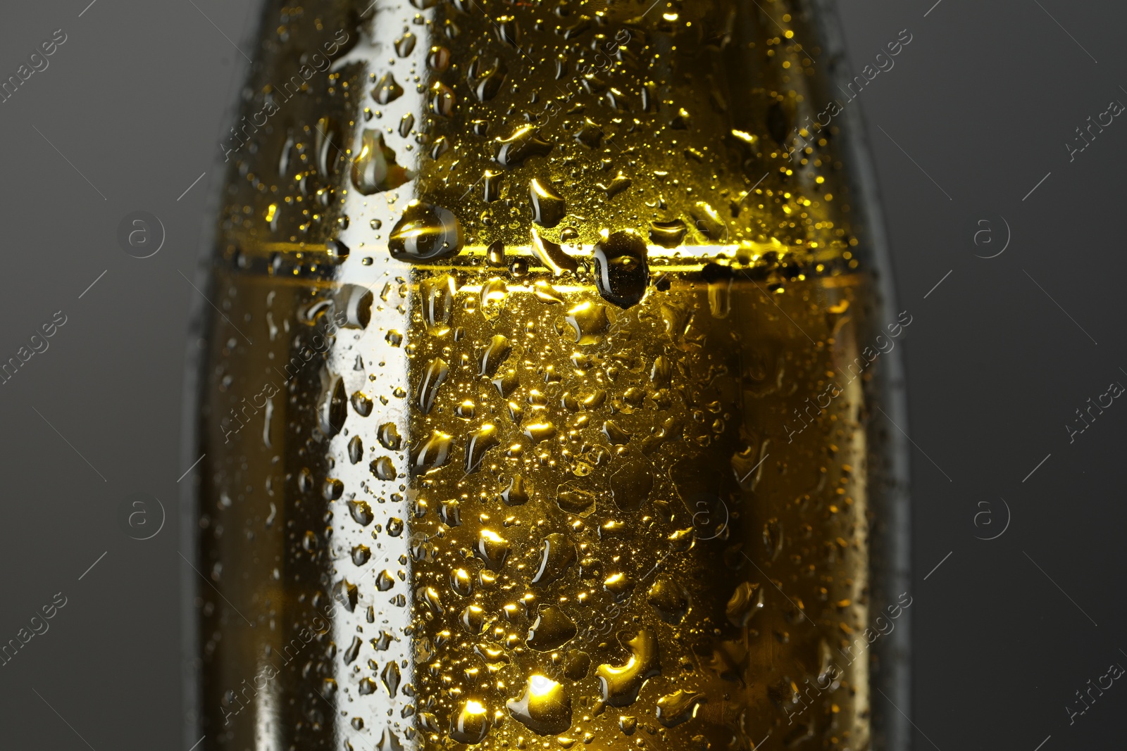 Photo of Glass bottle with condensation drops on grey background, closeup