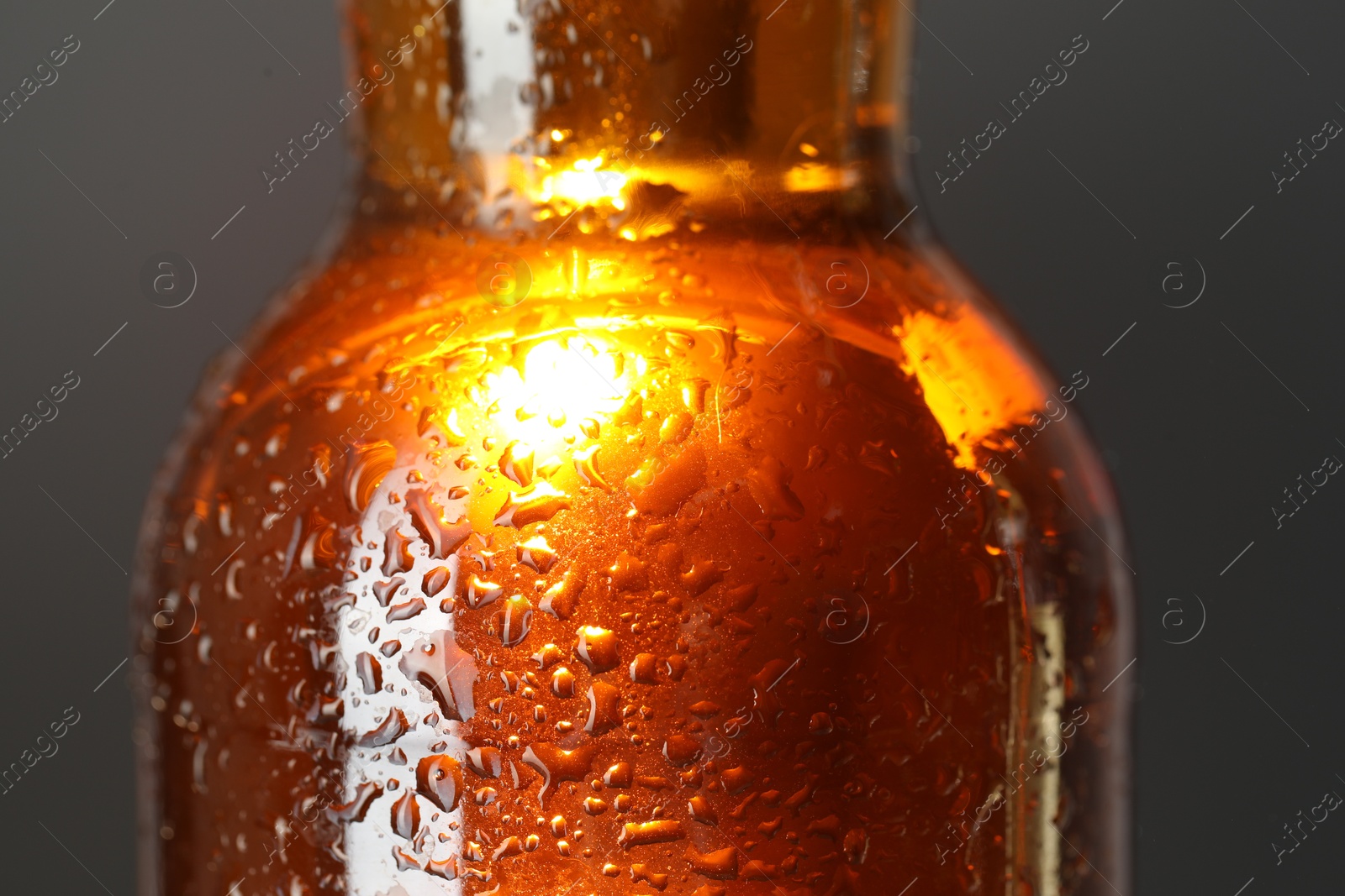 Photo of Glass bottle with condensation drops on grey background, closeup