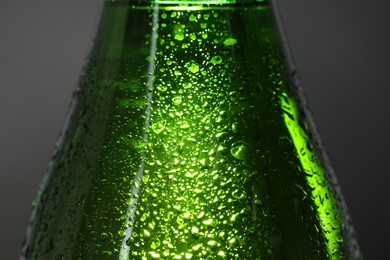 Photo of Glass bottle with condensation drops on grey background, macro view