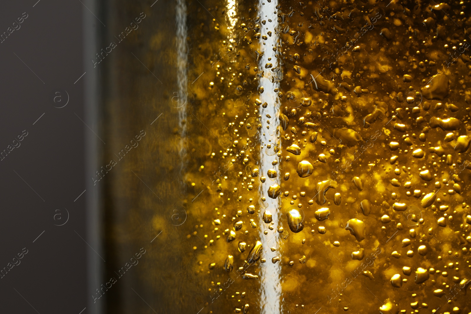 Photo of Glass bottle with condensation drops on grey background, macro view