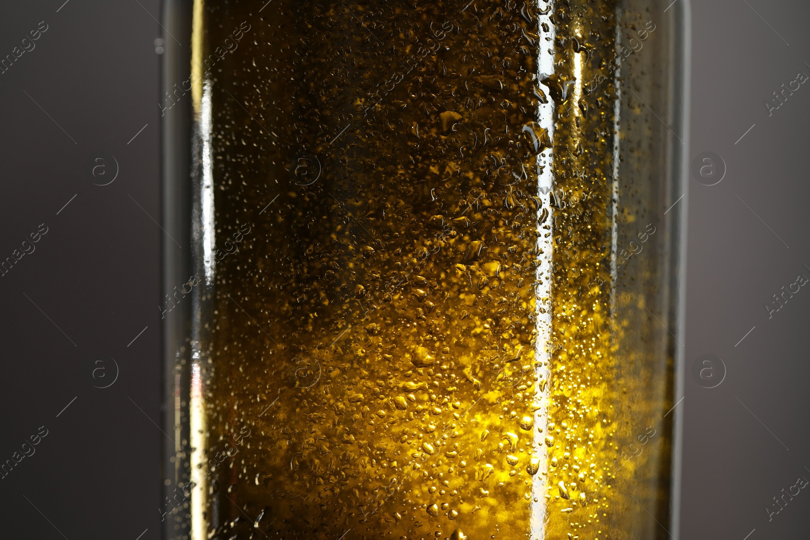 Photo of Glass bottle with condensation drops on grey background, closeup