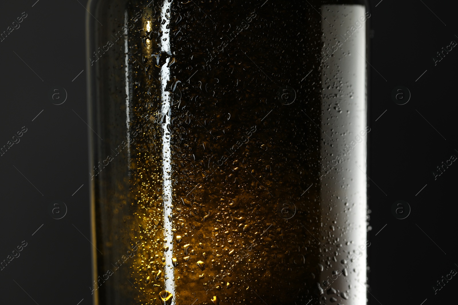 Photo of Glass bottle with condensation drops on grey background, closeup