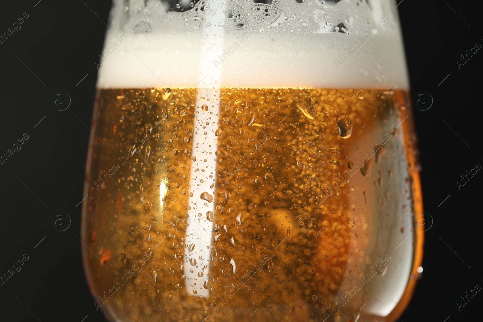 Photo of Glass of beer with condensation drops on black background, macro view