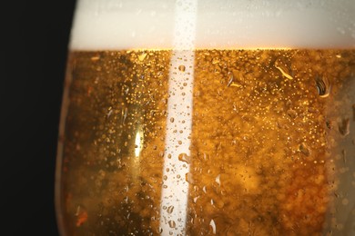 Photo of Glass of beer with condensation drops on black background, macro view