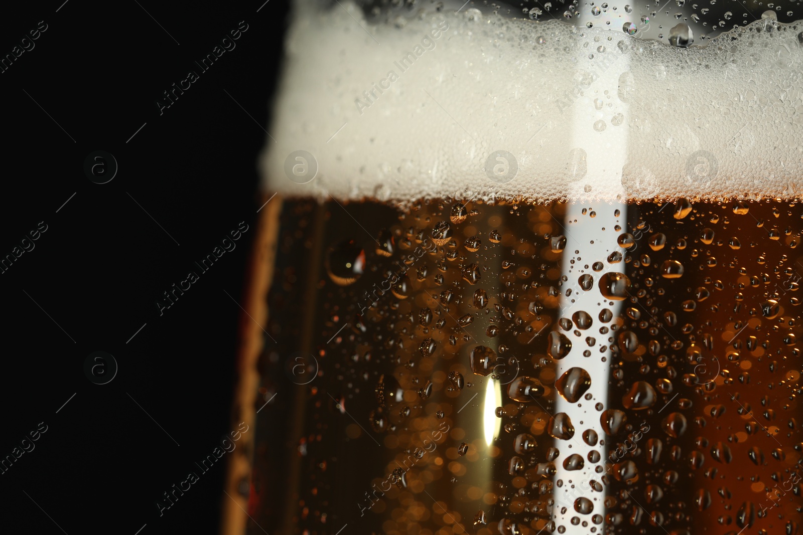 Photo of Glass of beer with condensation drops on black background, macro view. Space for text