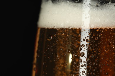 Photo of Glass of beer with condensation drops on black background, macro view. Space for text